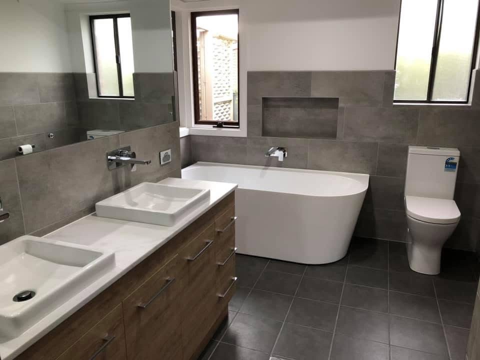 Completed bathroom renovation with tiled walls and freestanding bath